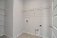 Spacious laundry with built-in linen shelving near your primary bedroom downstairs.  **All photos are of a previously constructed Covington floorplan.**