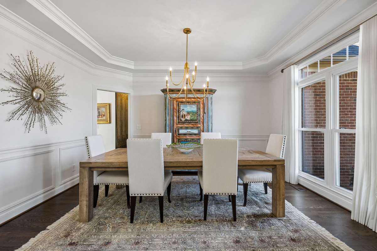 Stunnng dining room with custom wall moulding, trey ceiling, designer lighting and Hunter Douglass drapes.