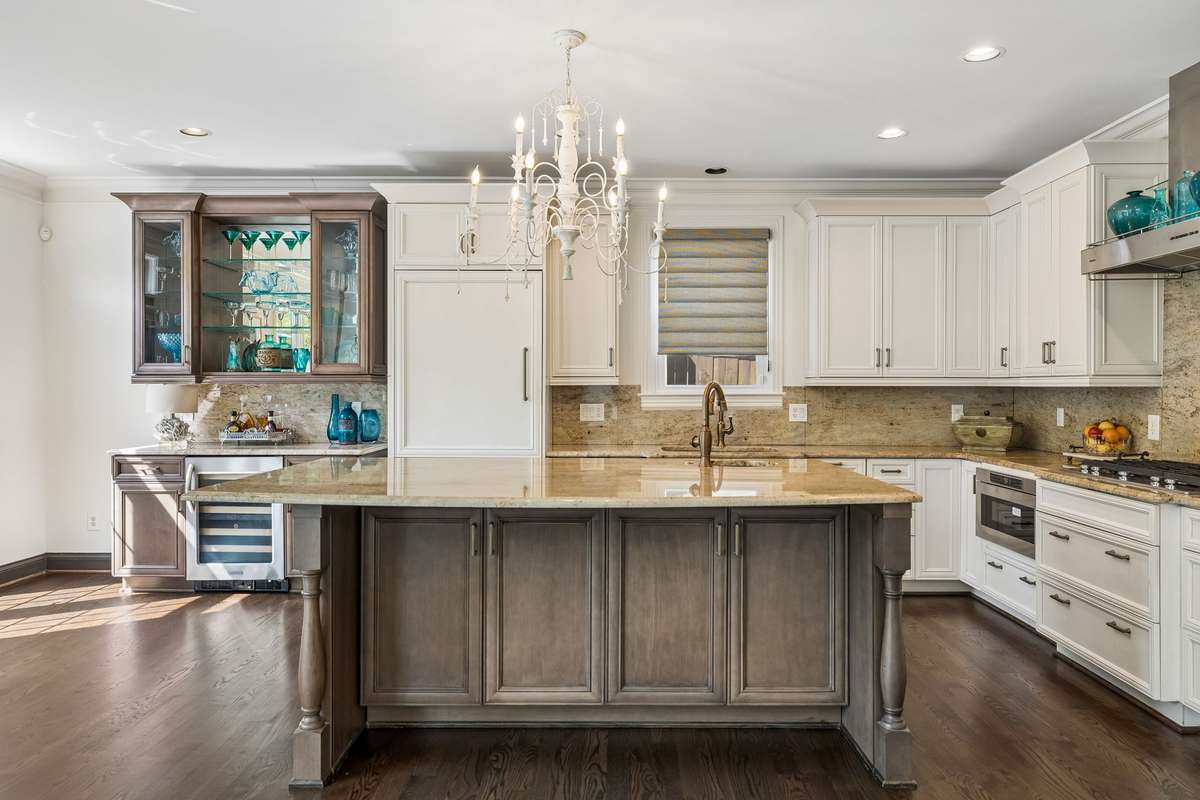 Popular and on trend two tone cabinetry. Built-in custom bar cabinet with tempered glass and wine cooler.