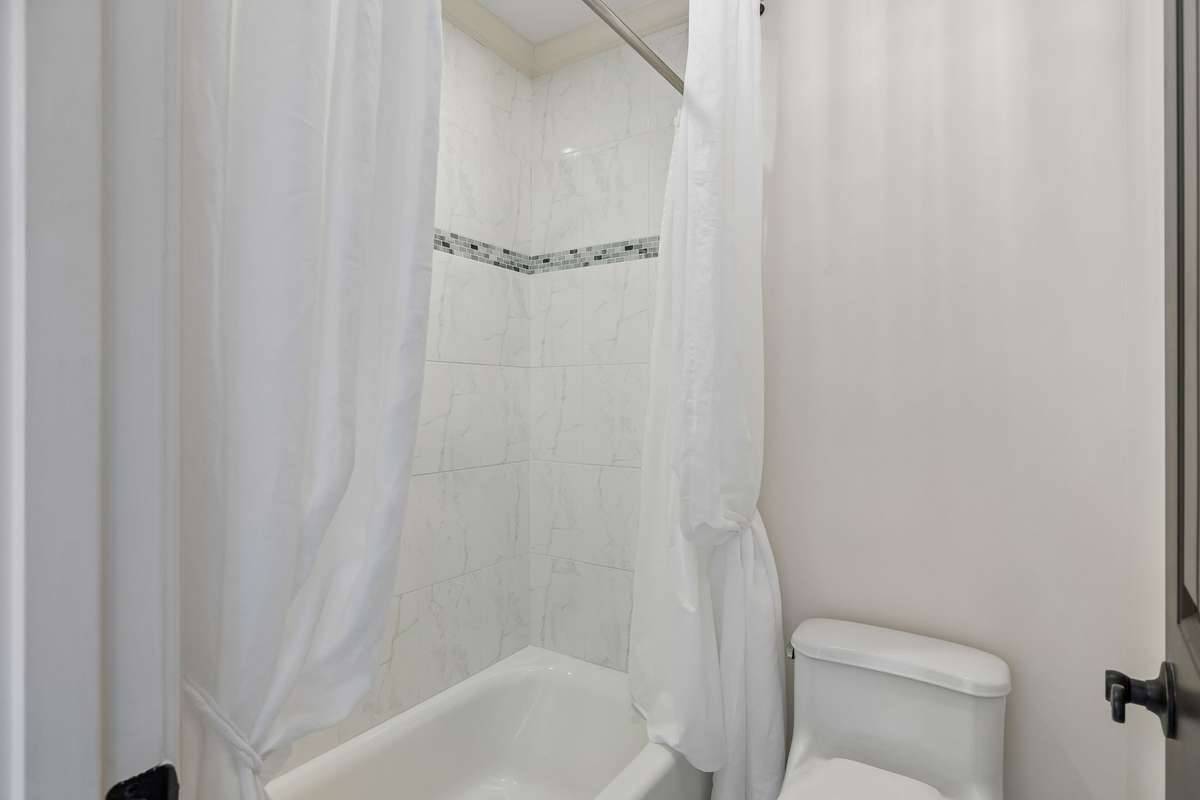 Floor and tub of ensuite has black and white beaded trim with white tile.