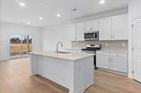 Kitchen with quartz countertops and stainless steel appliances
(photo is of a finished similar home- options and colors may vary in actual home)