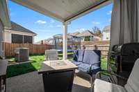Fully fenced backyard featuring a covered patio complete with fan!