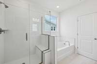 Luxurious primary bathroom featuring a beautifully tiled shower with a built-in seat and a soaking garden tub for ultimate relaxation.