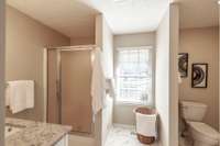 Renovated primary bathroom features elegant tile flooring and a bright, modern feel.