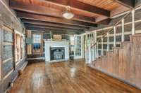Glass French doors separate the living room from the hallway. Wood burning stove inside fireplace.