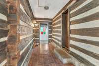 Concrete "dog trot" hallway which connects the two cabins and colored glass window featured at the front of the home.