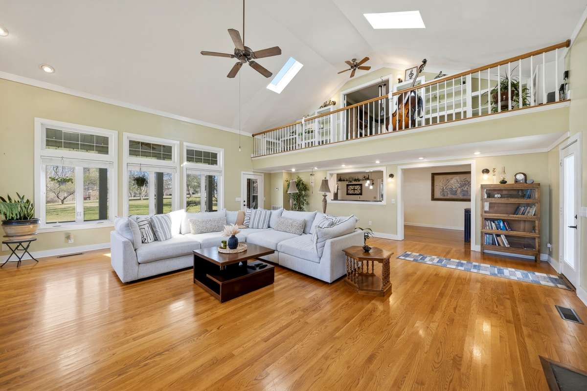 Living Room – Expansive living room with vaulted ceilings, skylights, and abundant natural light. Hardwood floors and large windows create an open, airy feel ideal for gathering and everyday living.