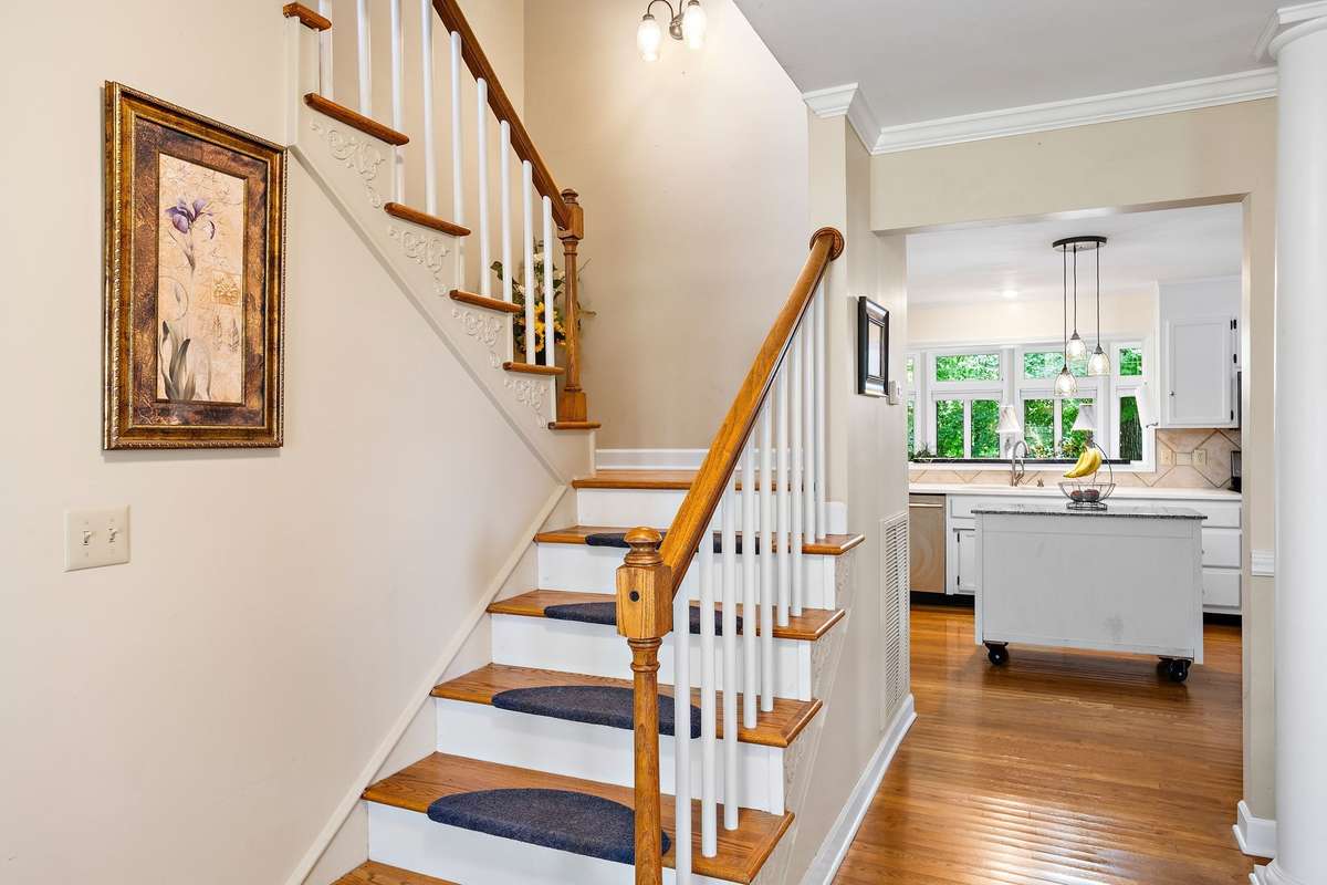 A welcoming foyer showcases hardwood flooring and a traditional staircase with wood accents and decorative trim. This central area provides easy access to the surrounding living spaces and upper level.