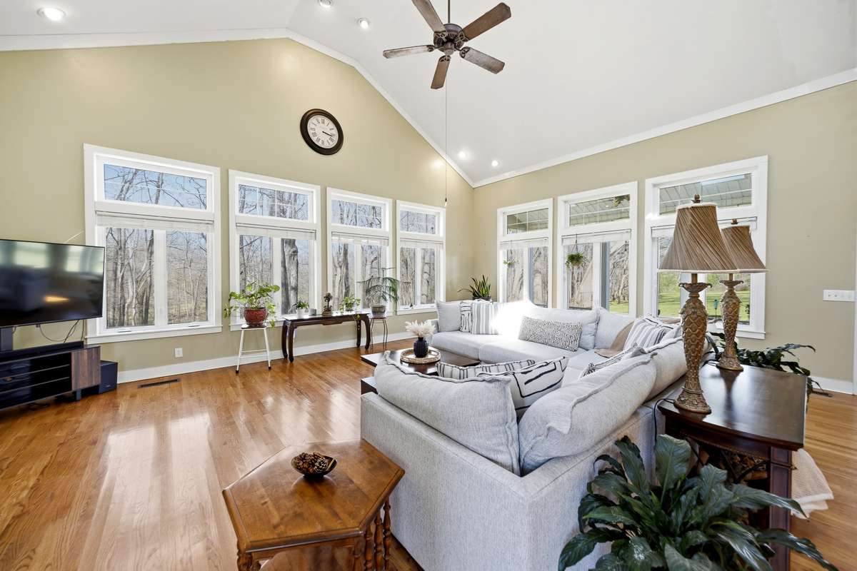 Living Room (Alternate View) – Stunning living room with soaring ceilings, expansive windows, and abundant natural light. Open layout and hardwood floors create an inviting space ideal for relaxing or entertaining.