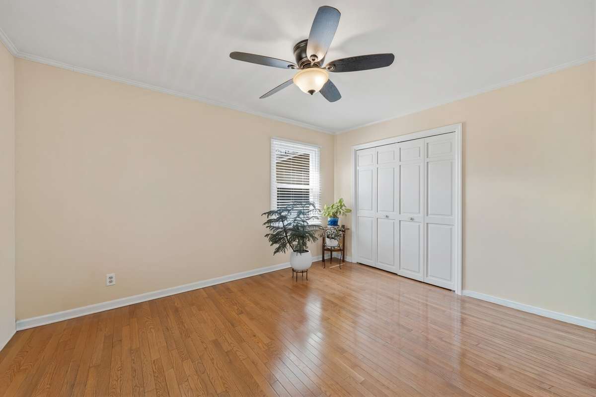 Bedroom – This versatile bedroom features beautiful hardwood flooring, neutral tones, and a ceiling fan for year-round comfort. A double-door closet offers ample storage, while natural light from the window enhances the bright and open feel.