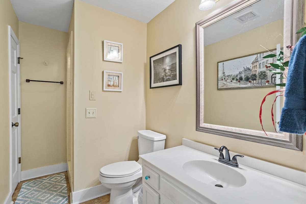 A well-maintained bathroom with a clean, bright vanity, framed mirror, and a walk-in shower design. Soft wall tones create a calm, refreshing atmosphere.
