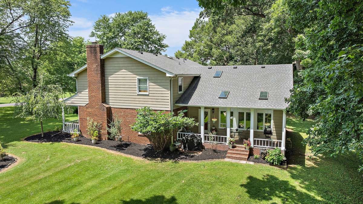 The rear exterior highlights the home’s architectural lines, multiple skylights, and extended porch. The landscaped backyard and surrounding trees offer privacy and natural beauty.