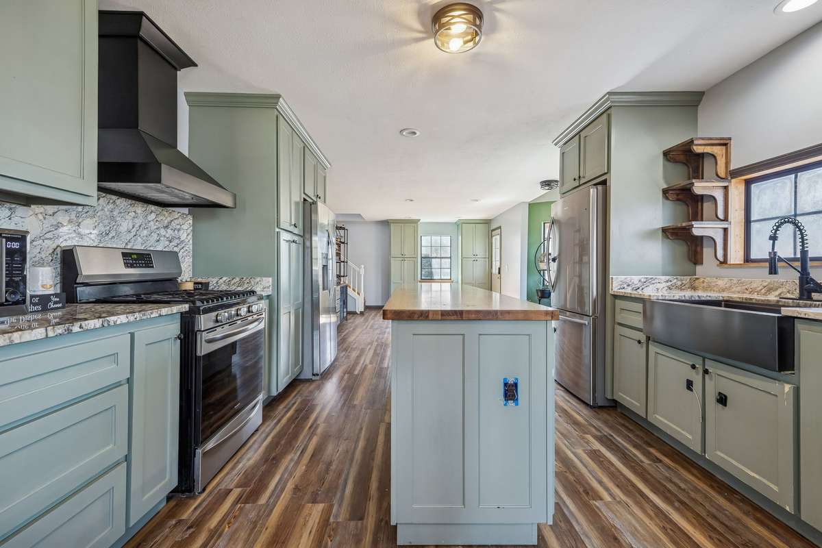 Enjoy the ample space this kitchen with island offers complete with gas stove and hood vent, newer farmhouse sink, 2 full size refrigerators, and custom pantry.