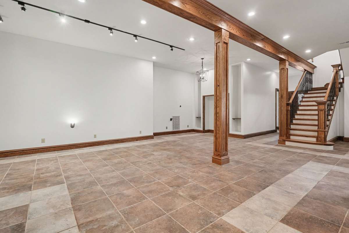 4000 sq ft basement with double sided fireplace and bar area.  Stairs leading to den/kitchen, far door leading to one cedar closet, bedroom (or can be gym with mirror on wall, electric shades