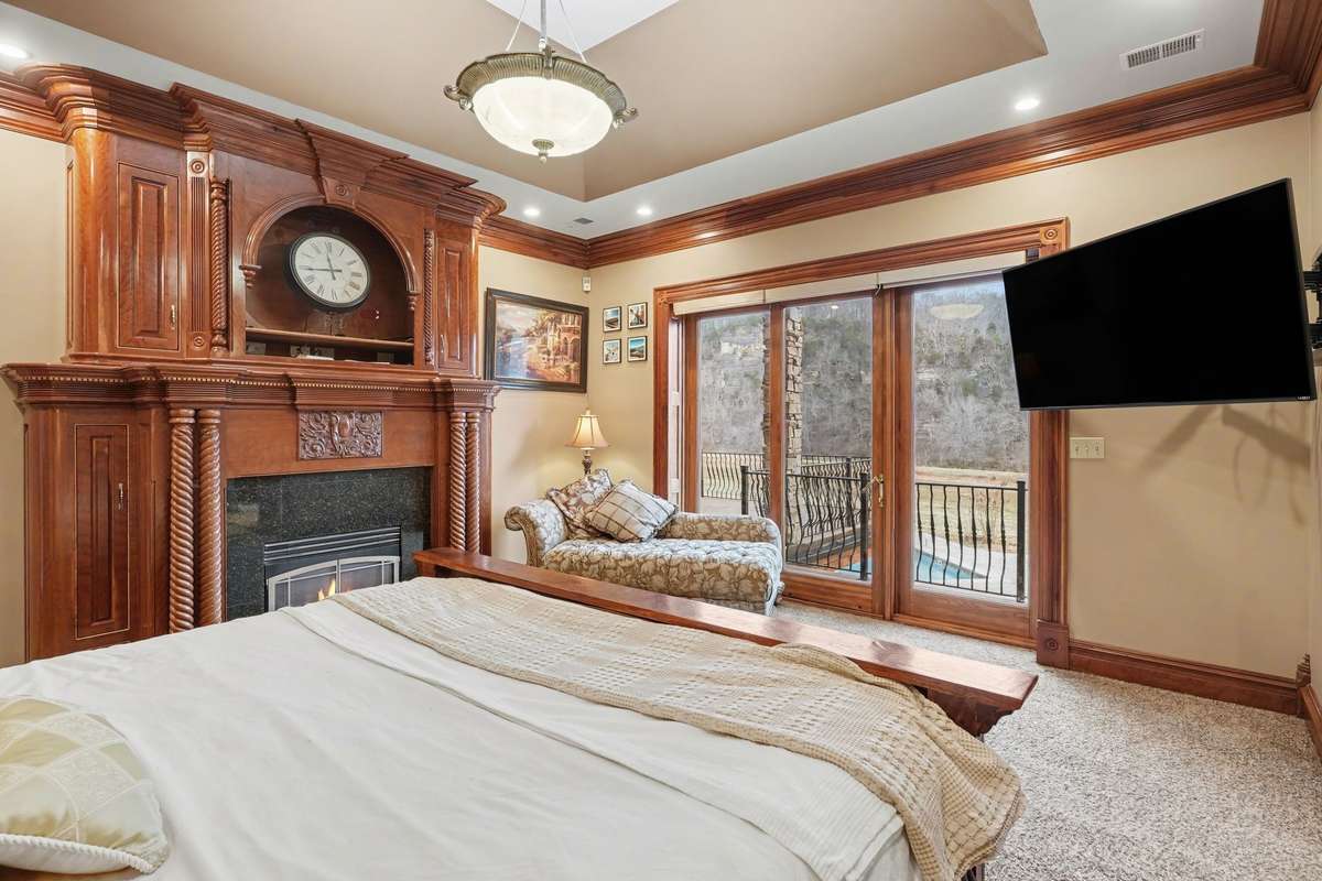 primary bedroom with fireplace and balcony with view to the pool