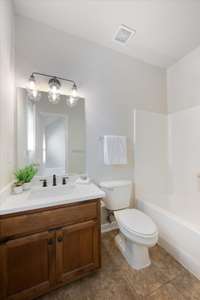 Private bath in secondary bedroom features new quartz vanity/sink, new faucet, and new fanity lighting.