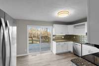 Large sliding glass doors to new deck and open back yard provide natural light to the kitchen and living area.