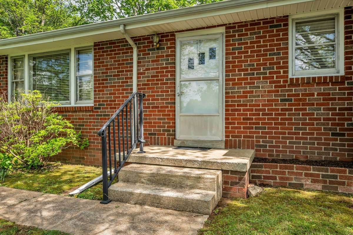 Front door with sturdy metal rail & a place for your favorite flowers to the right of the porch.