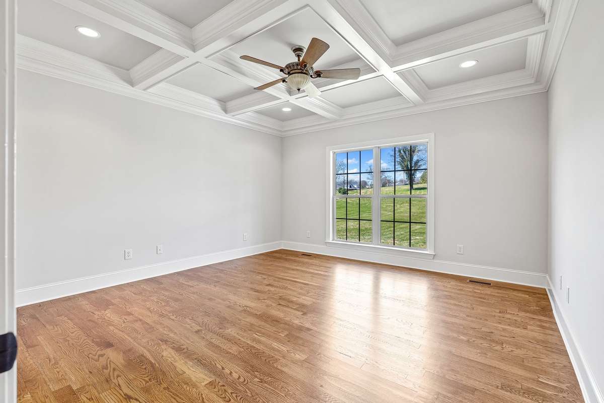 The Primary Suite located on the main level for privacy features a beautifully detailed ceiling.