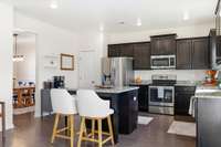 Spacious kitchen with center island, dark cabinetry and granite countertops.