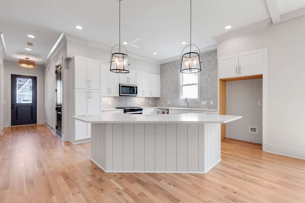 The kitchen boasts modern fixtures, white cabinets, and a tile backsplash extending up the wall, all illuminated by recessed lighting! 6369 Alamo Pl  Nashville, TN