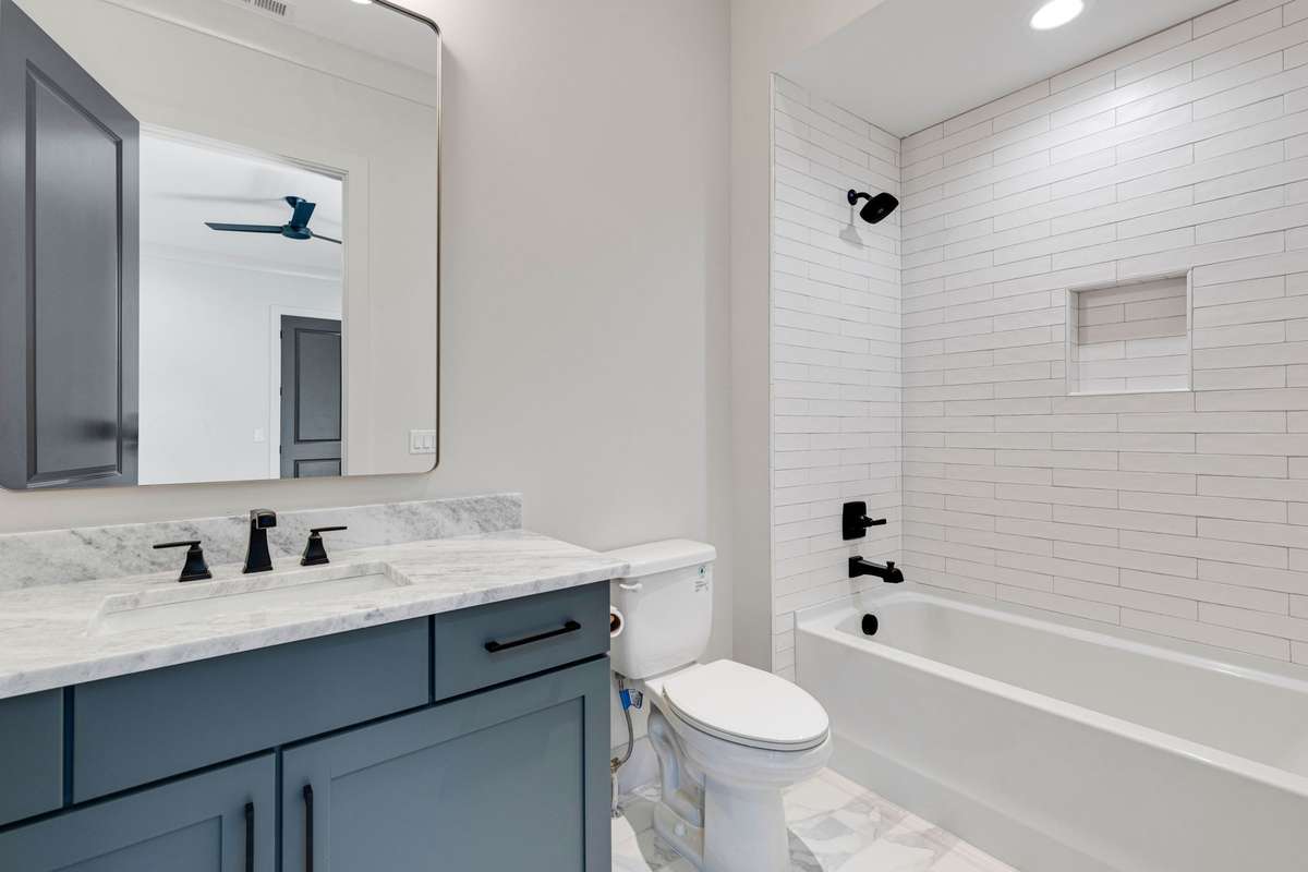 The ensuite bathroom in the second bedroom features black hardware accents complementing the white-tiled combo shower/tub and single vanity. 6369 Alamo Pl  Nashville, TN