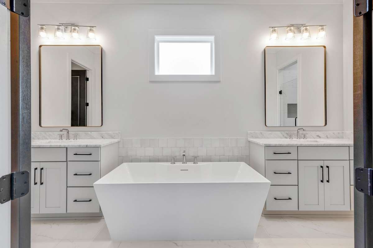The ensuite bathroom features split double vanities and elegant tile flooring with a large tub that invites luxury and relaxation!  6369 Alamo Pl  Nashville, TN