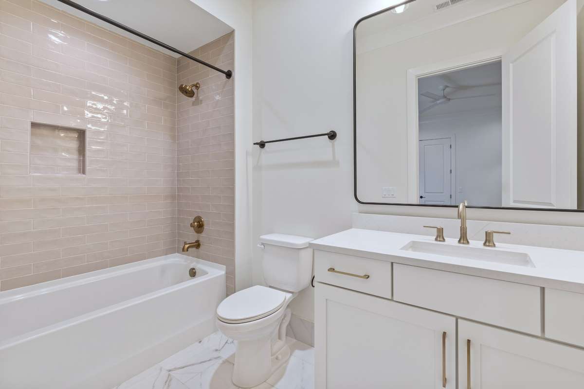 Private bath with single vanity, tile flooring, & pink tiled combo tub & shower. 6371 Alamo Pl Nashville TN 37209