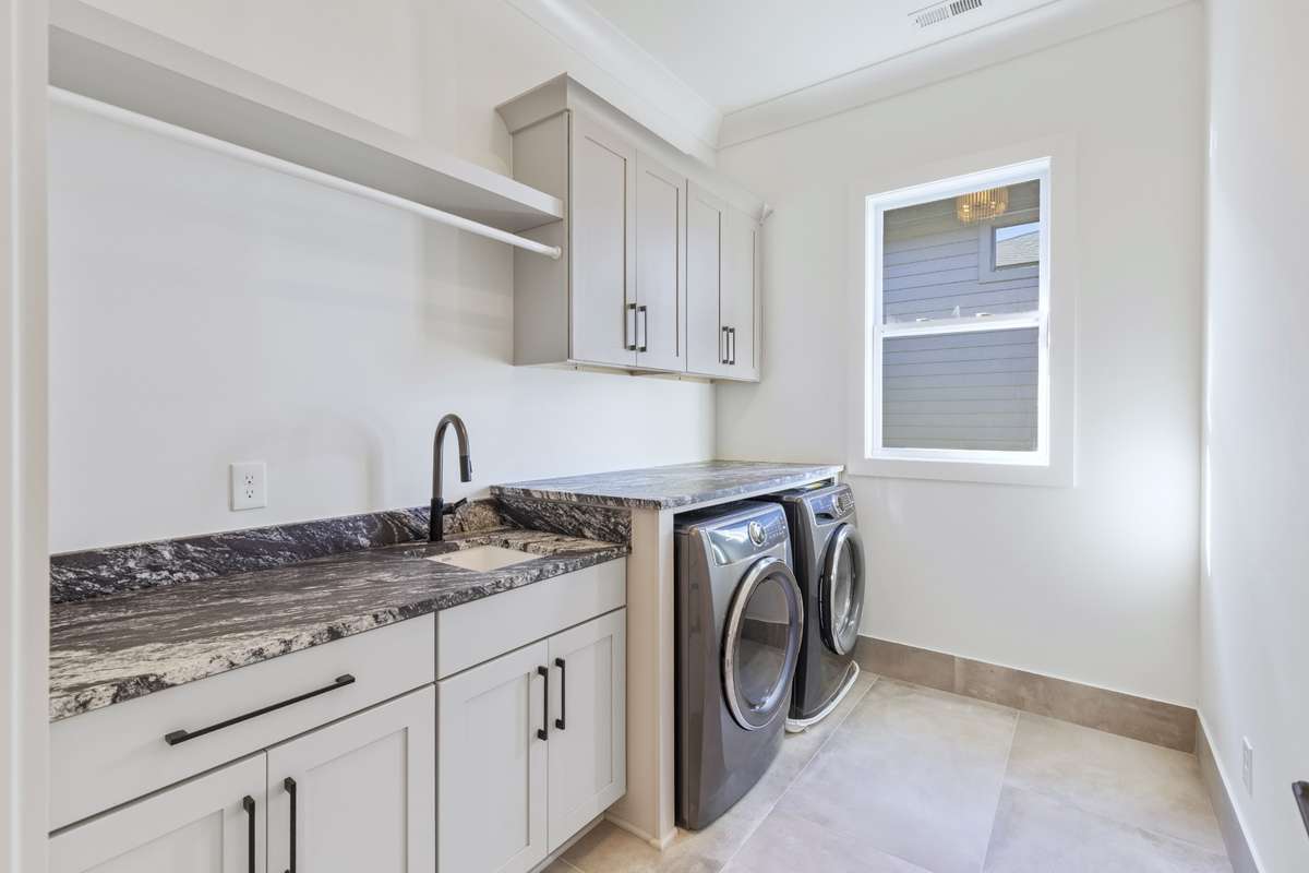 Large laundry room with oversized counter, custom cabinets, clothes wrack, & tile flooring. 6371 Alamo Pl Nashville TN 37209