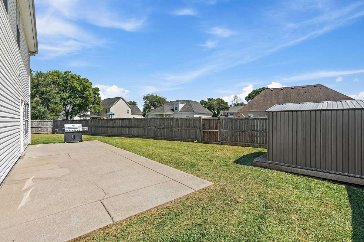 Fully fenced backyard with 9x10 metal utility shed for storage.