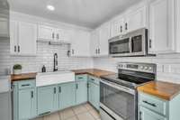 with stainless steel appliances, a tile backsplash and butcher block countertops.