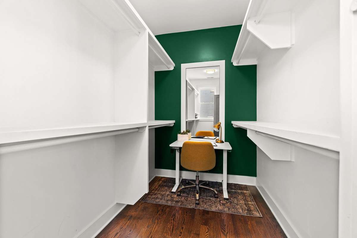 Walk-in primary closet with built-in shelving and even big enough to even have a work space!