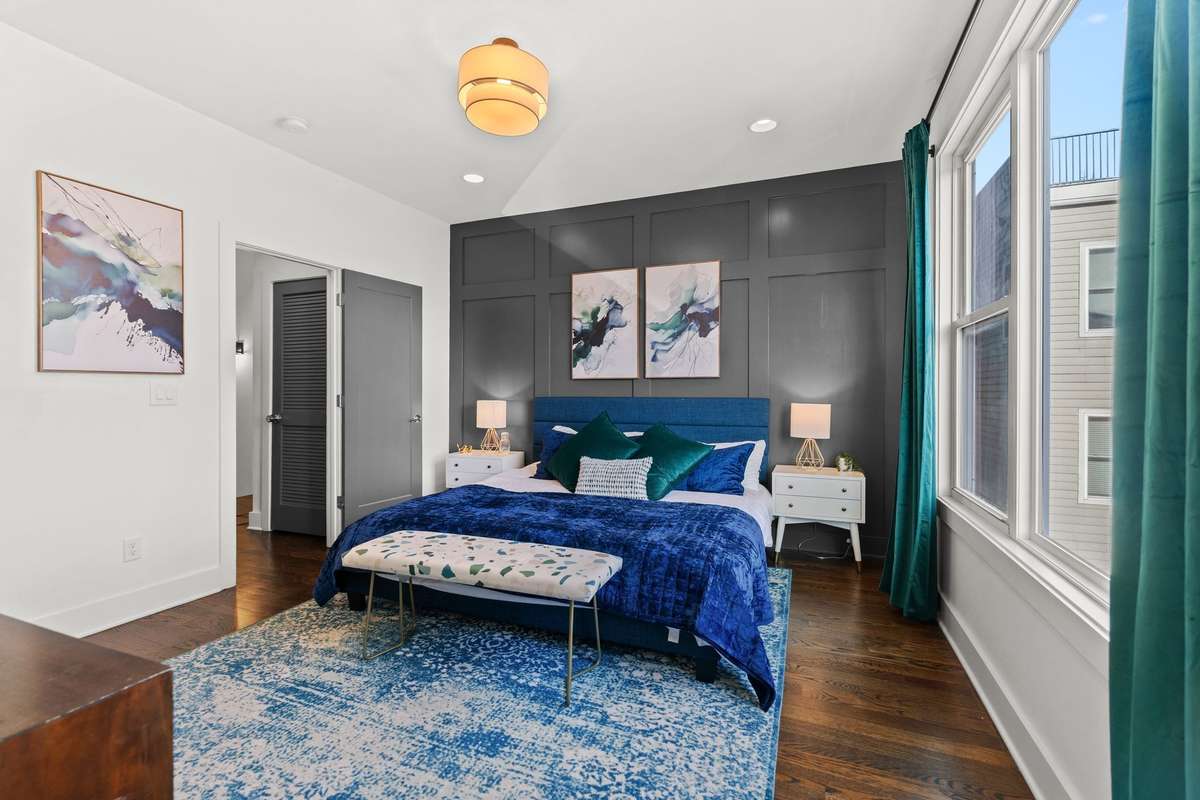 Primary bedroom with large windows, wood floors, massive walk-in closet, and an ensuite bathroom.