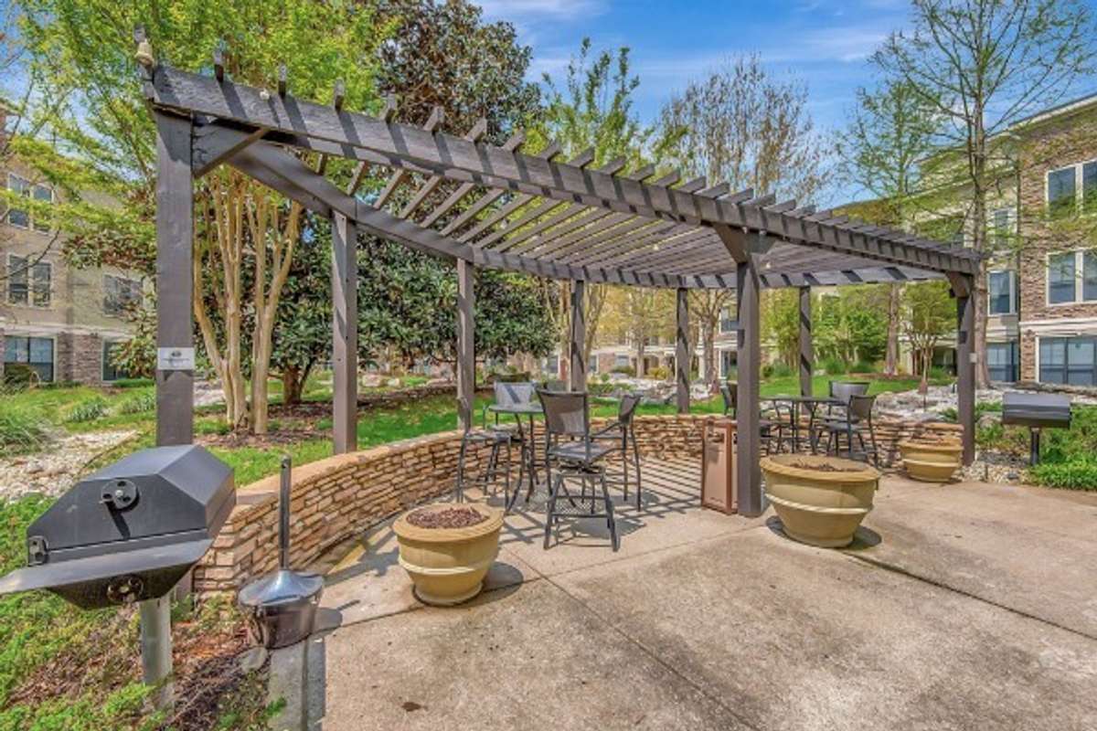 Outdoor community patio with grills, walkways, and pergola seating.