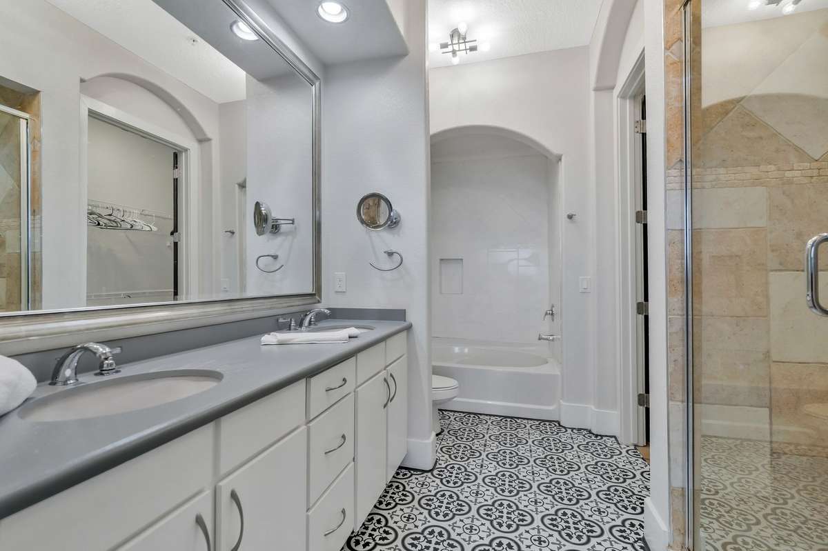 Primary bathroom with double vanity, tile flooring, soaking tub, walk-in shower, and massive walk-in closet!