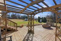 Extensive hardscape featuring a firepit, built-in grill surround, and wood pergola