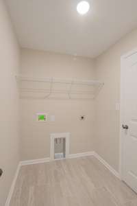 Large Laundry Room with Tile Flooring and Shelving! Laundry Connects to the Primary Closet Hallway and The Main Hallway!