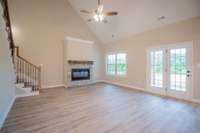 EXAMPLE>>>Large Living Room with a Stone Fireplace, Floating Wood Mantle, Vaulted Ceiling, Access to the Covered Patio and Tons of Natural Lighting!