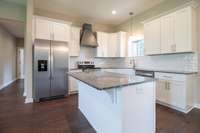 Gorgeous bright white kitchen accented with darker stone countertops and stainless appliances!