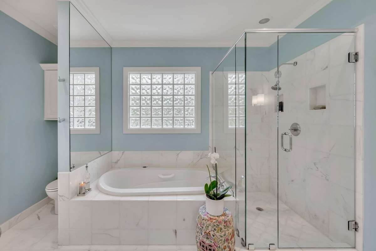 The luxurious all-marble spa-like primary bathroom features a hydrotherapy tub, walk-in shower, and separate double vanities.