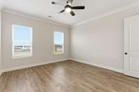 Primary bedroom has two large windows for natural light and ceiling fan