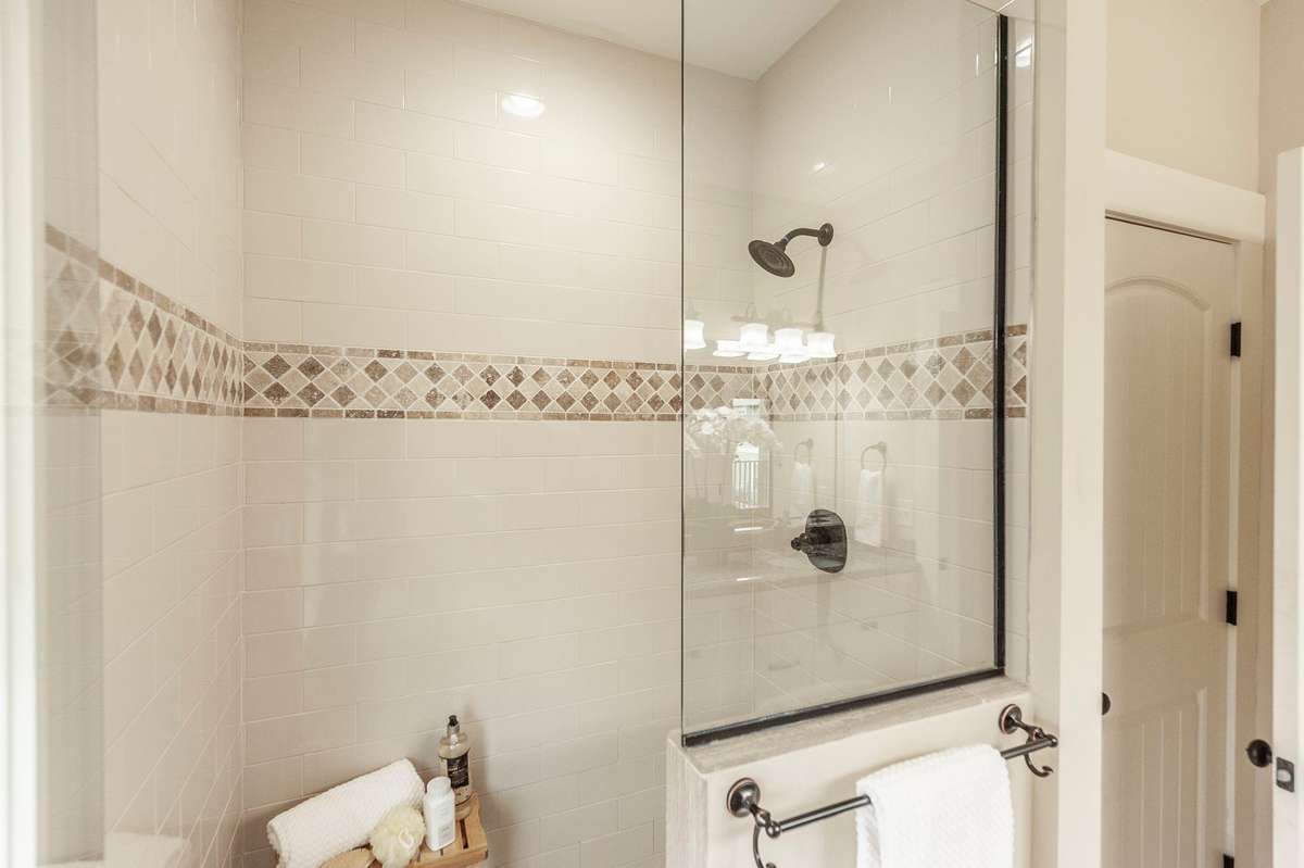 A large tiled shower with frameless glass doors adds a sleek, modern touch.