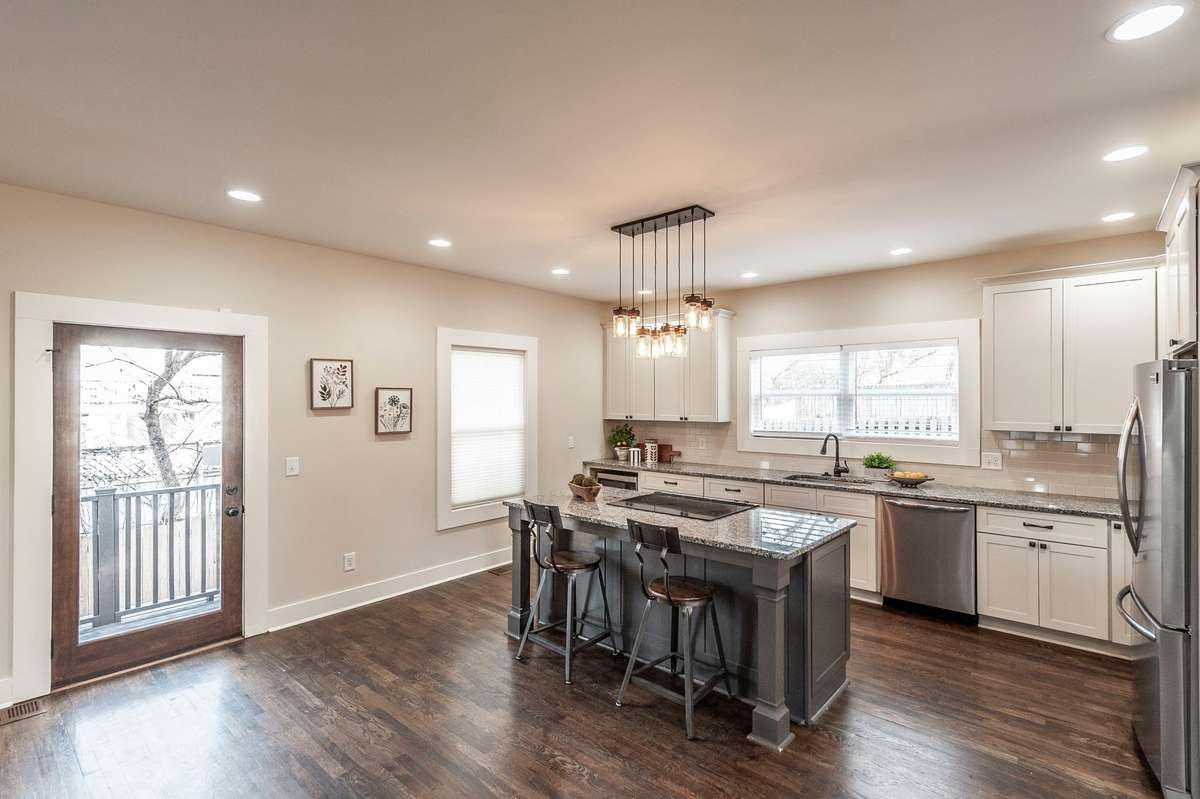 The bright and stylish kitchen features soft white cabinetry, granite countertops, and a large center island.