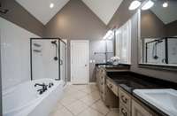 Primary suite features an air jet tub, tile shower, double vanity seperated by dressing station