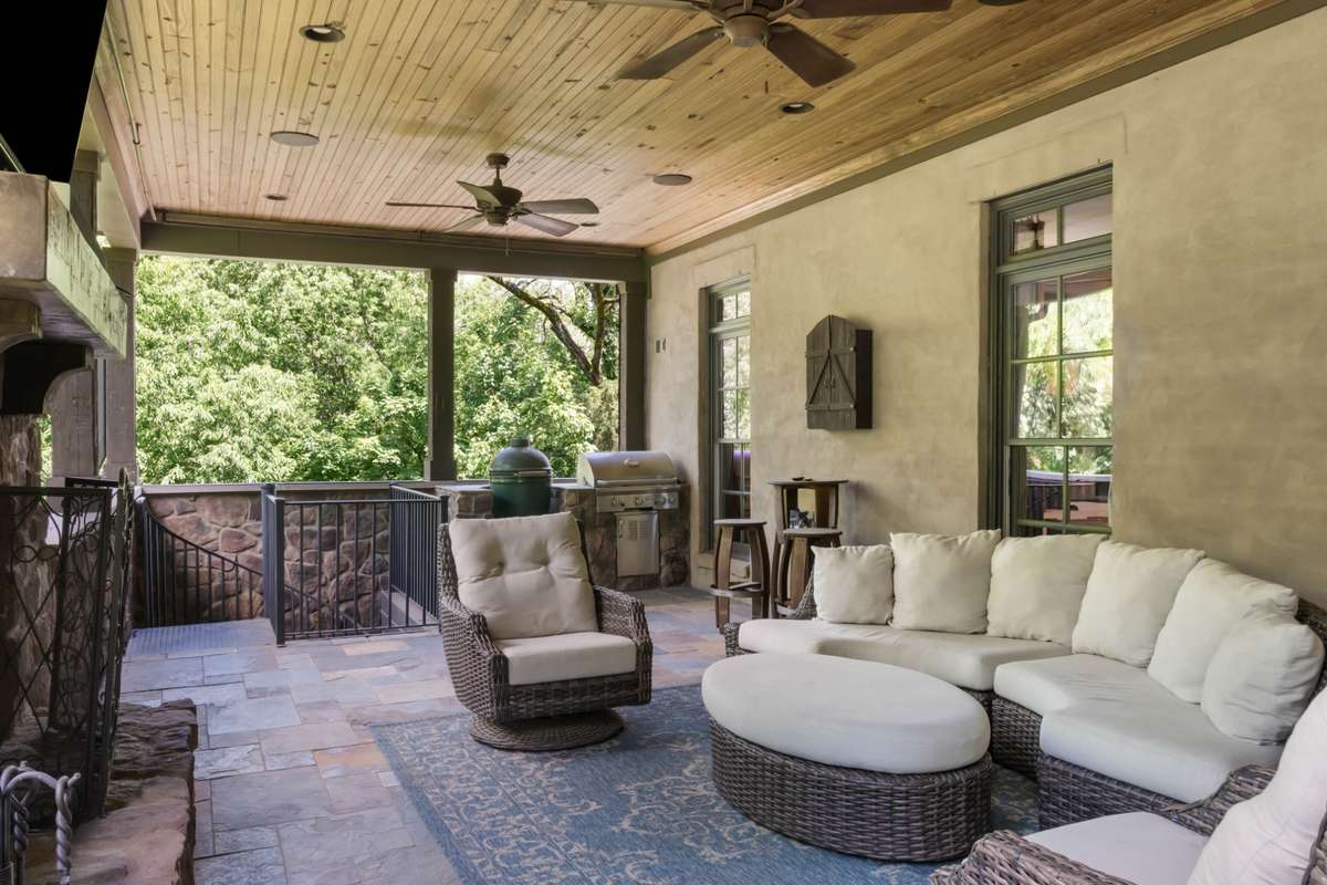 Alternative view of main floor porch. The staircase in the background takes you to the ground level covered patio that has a another two-sided fireplace and ideal covered party spot next to the future pool.