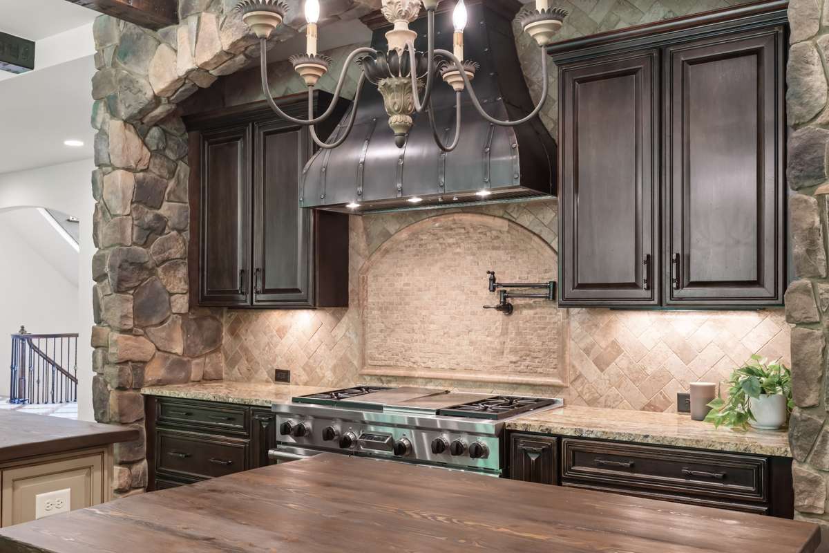 Dual fuel Wolf range with griddle, grill, & double oven, pot filler, pro hood vent. Cabinets put spices, ingredients, and pots & pans within arm's reach.