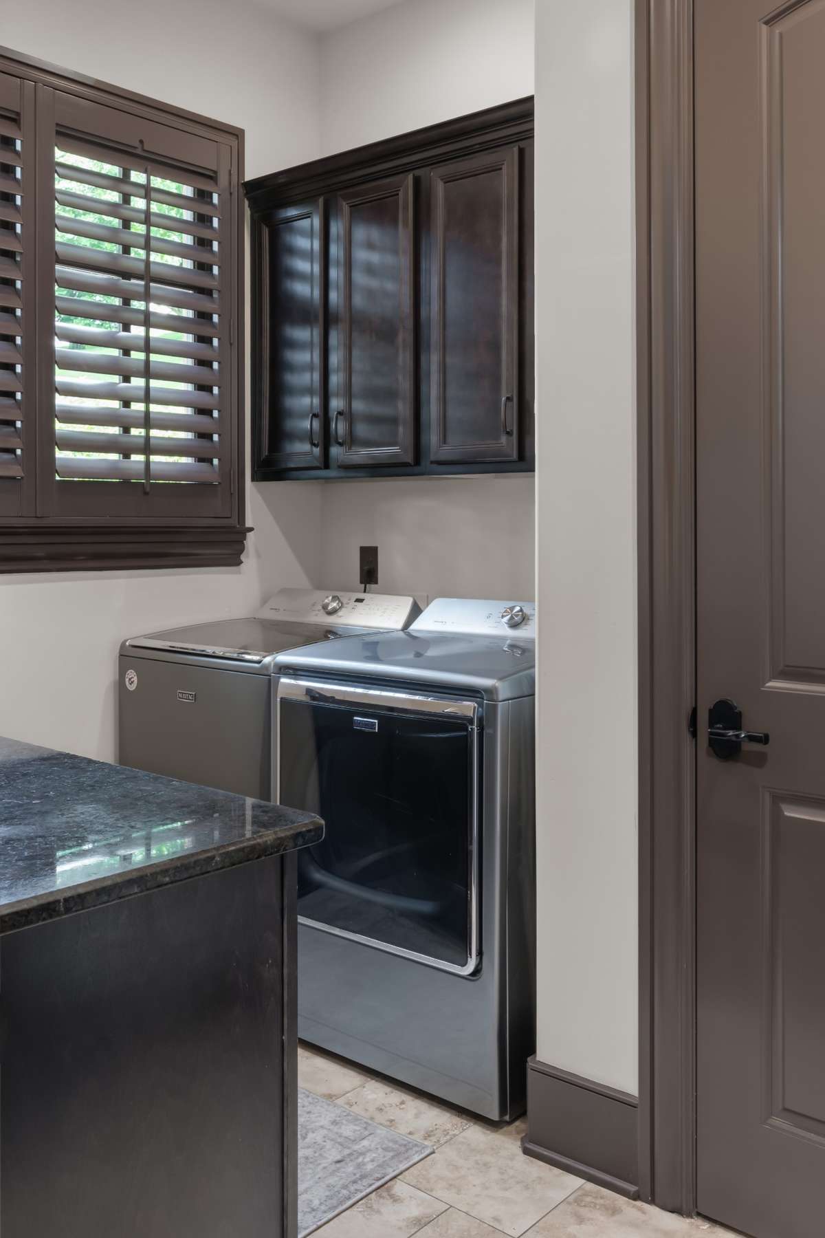 Main floor laundry with chute, sink, cabinets, and granite folding counter.