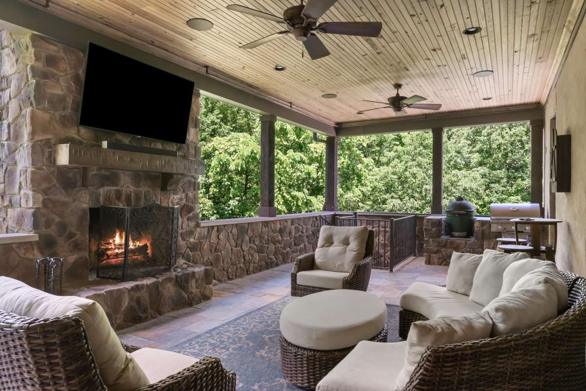 Main floor covered porch off the great room with fireplace, video connection, built-in audio, ceiling fans, and grill station.