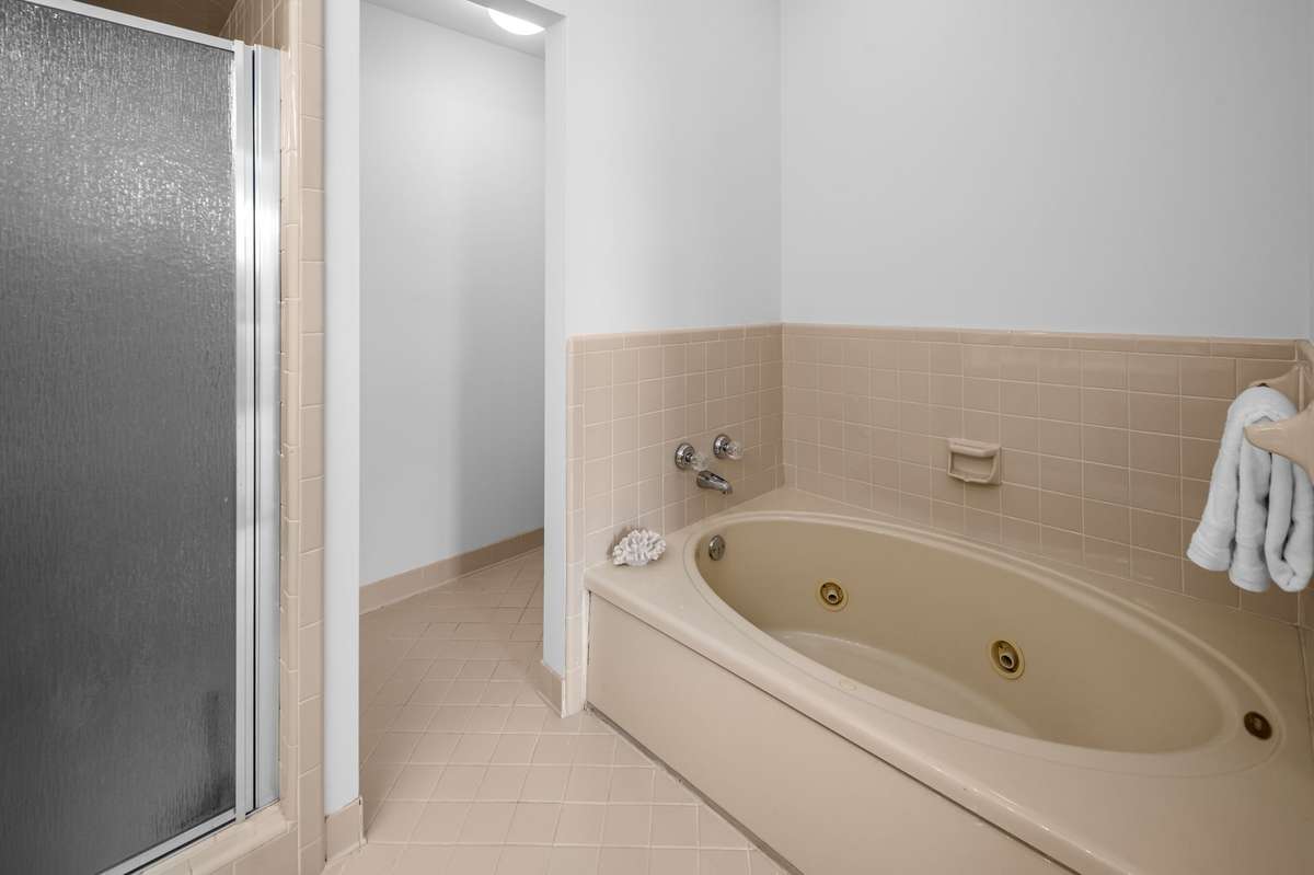 The primary bathroom has a separate shower and a jacuzzi bathtub. There is a deep linen closet behind the door.