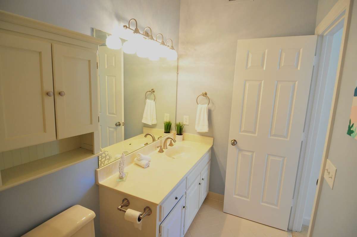 Secondary bathroom has a large vanity and storage cabinet over the toilet.